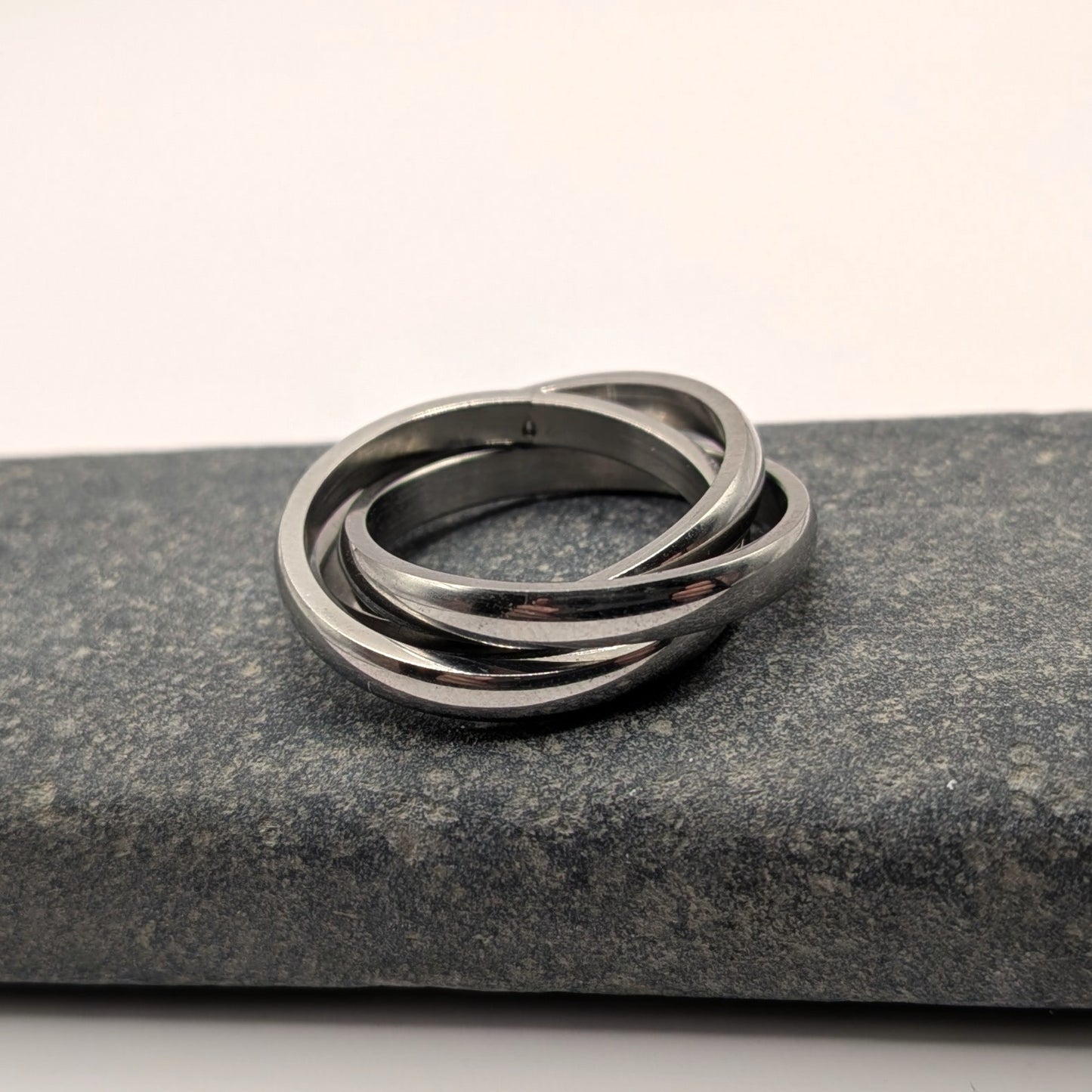 Stack of three silver rings on a dark stone surface