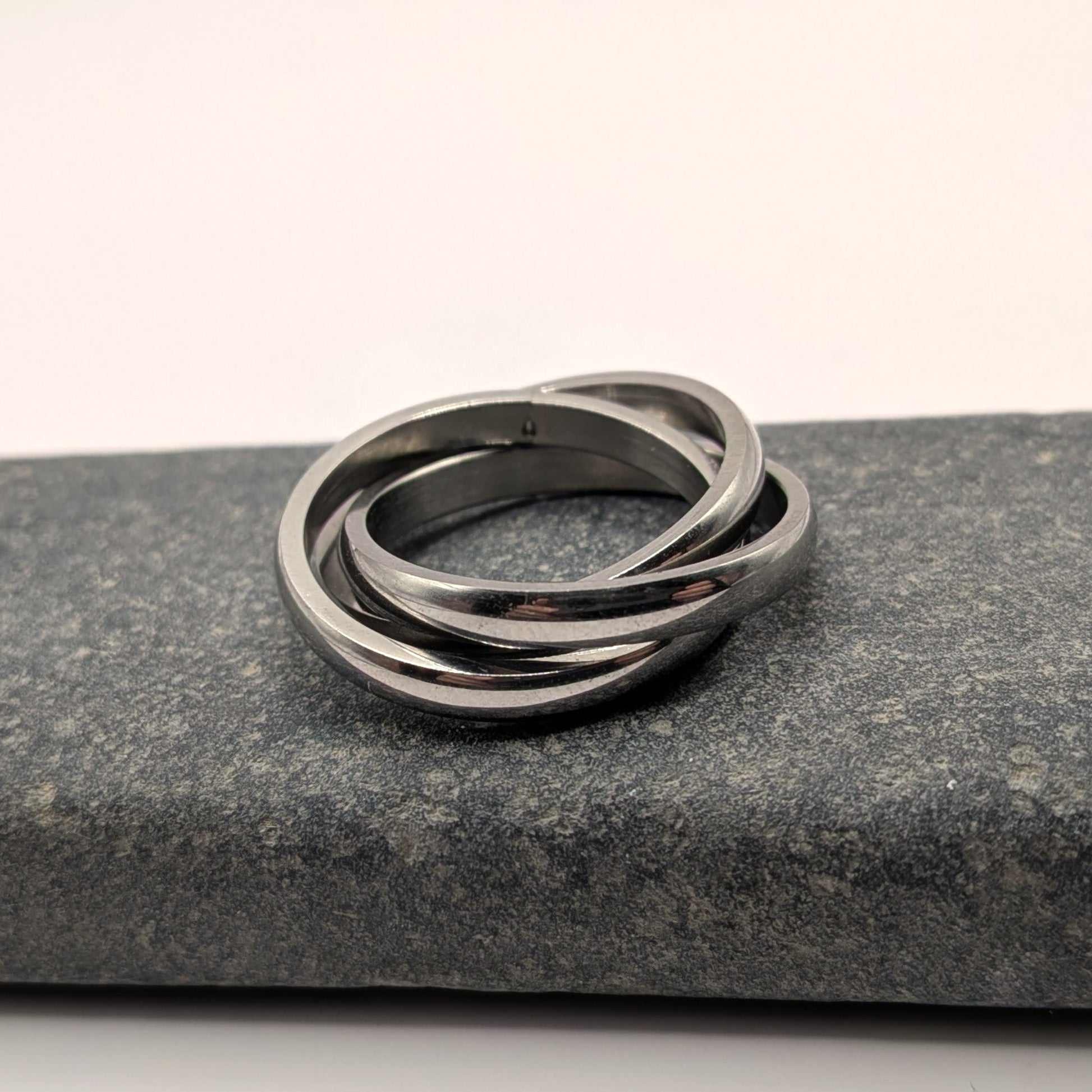 Stack of three silver rings on a dark stone surface