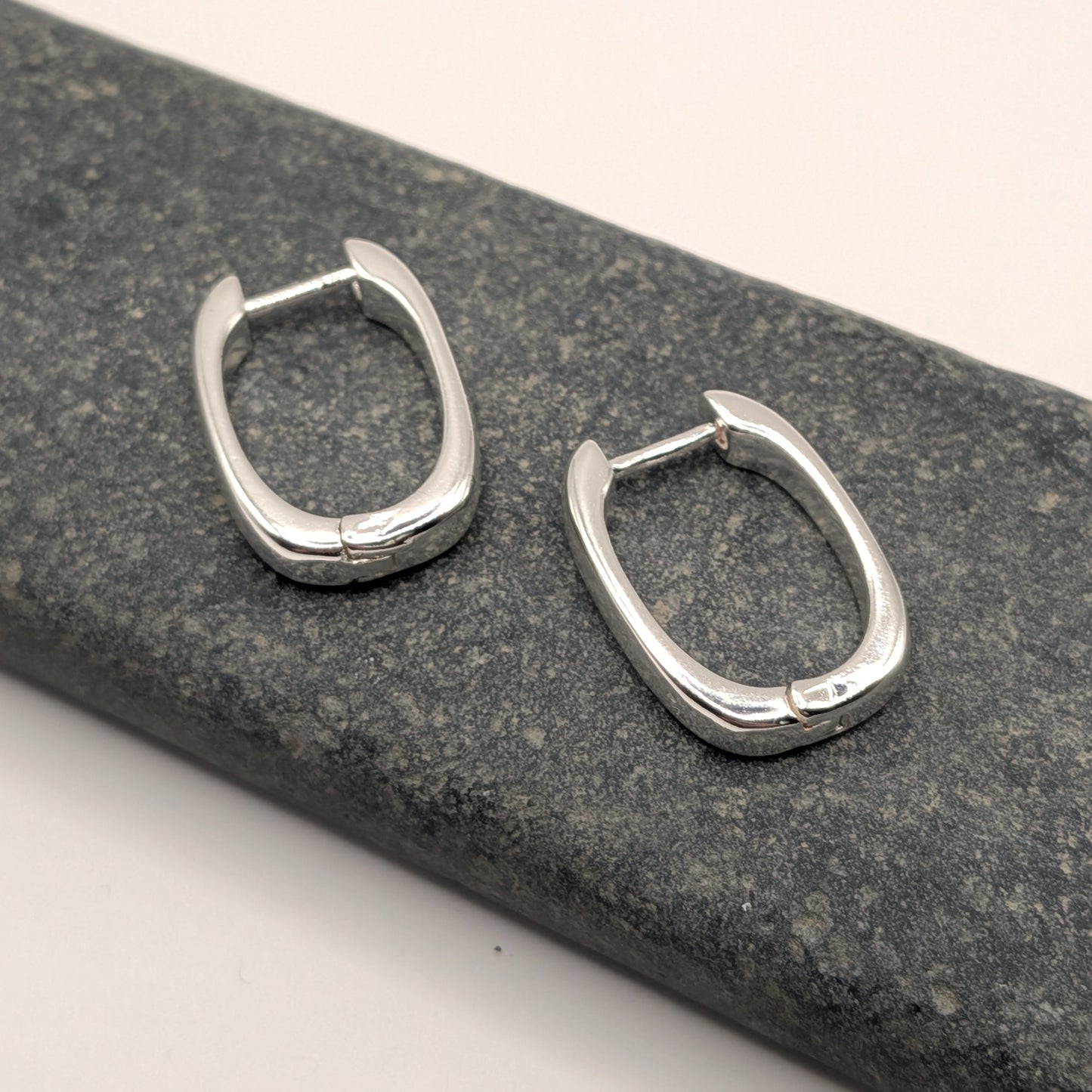 Pair of silver hoop earrings on a textured gray surface