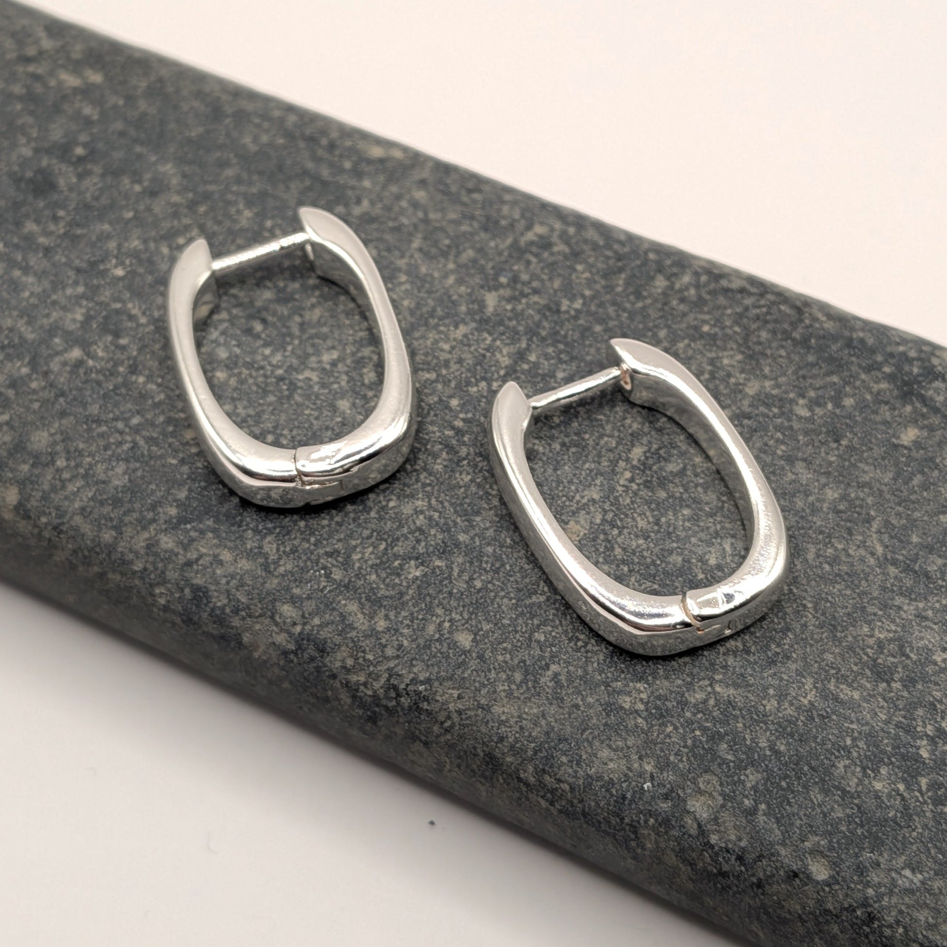 Pair of silver hoop earrings on a textured gray surface