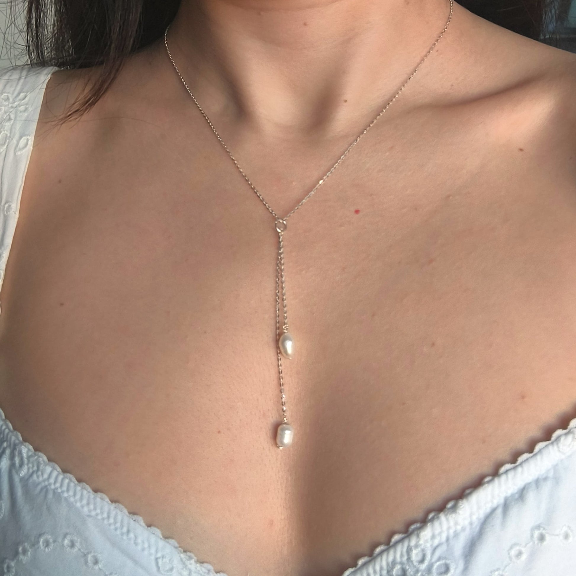 Pearl necklace worn by a person with a white top