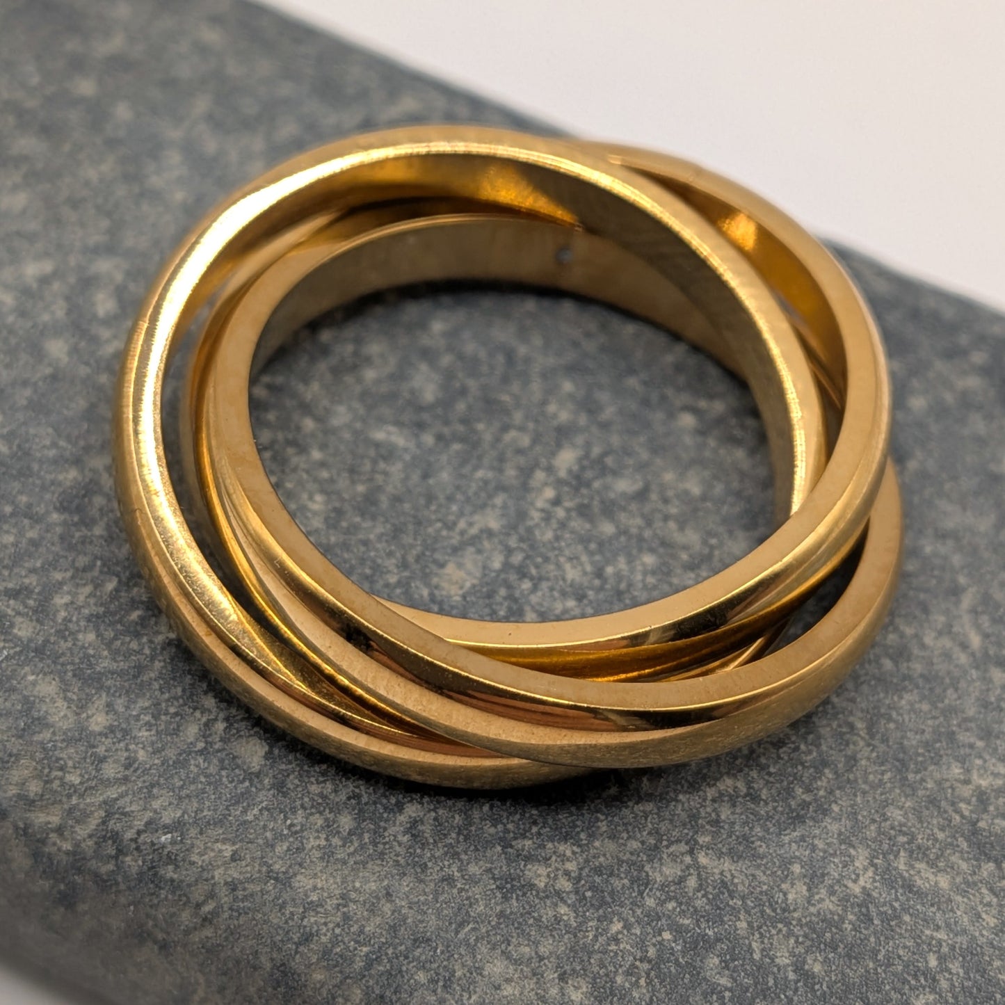 Triple stacked ring in 18k gold plating on grey stone surface