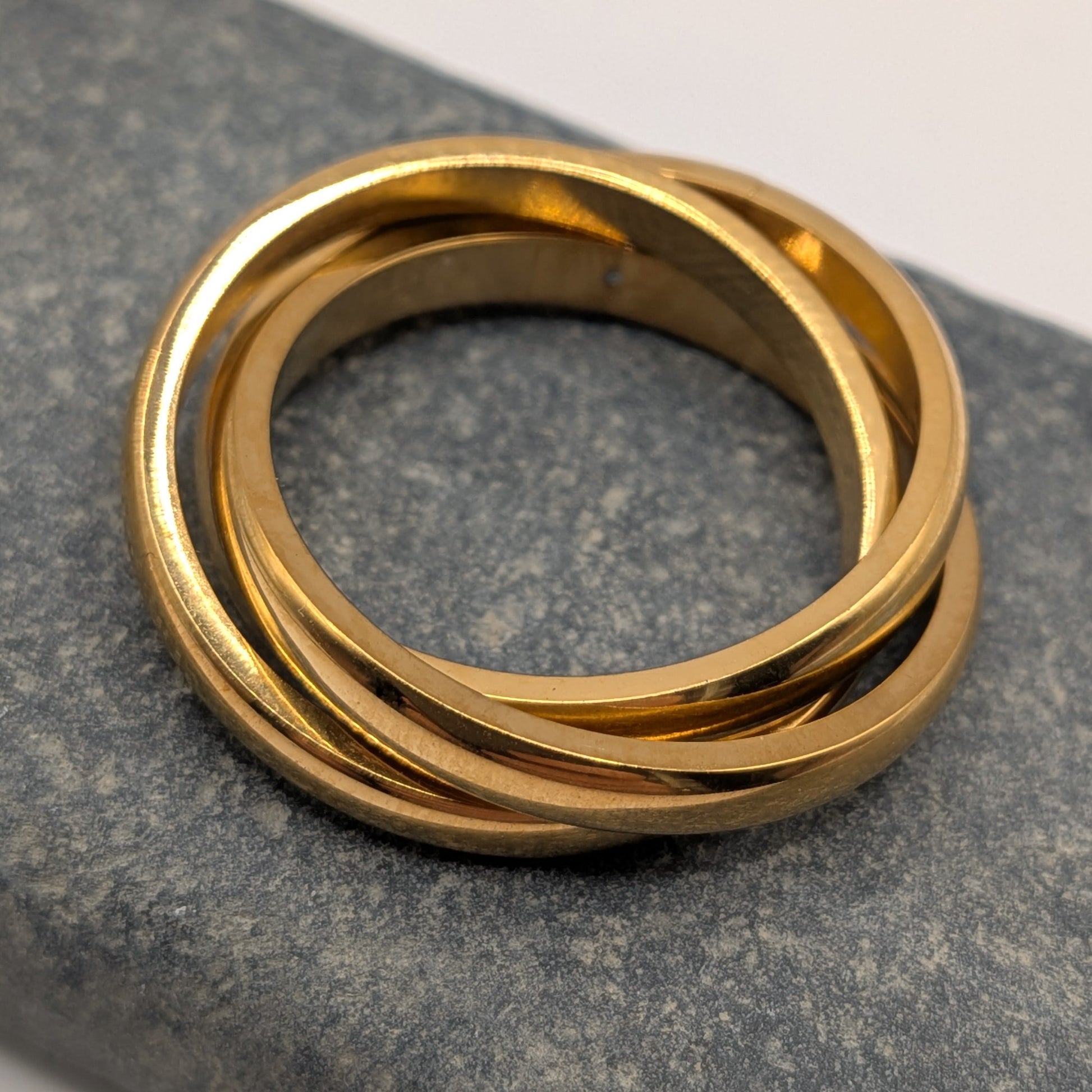 Triple stacked ring in 18k gold plating on grey stone surface