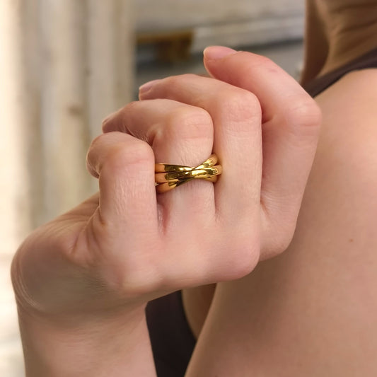 Close-up of a hand wearing a gold ring with a blurred background
