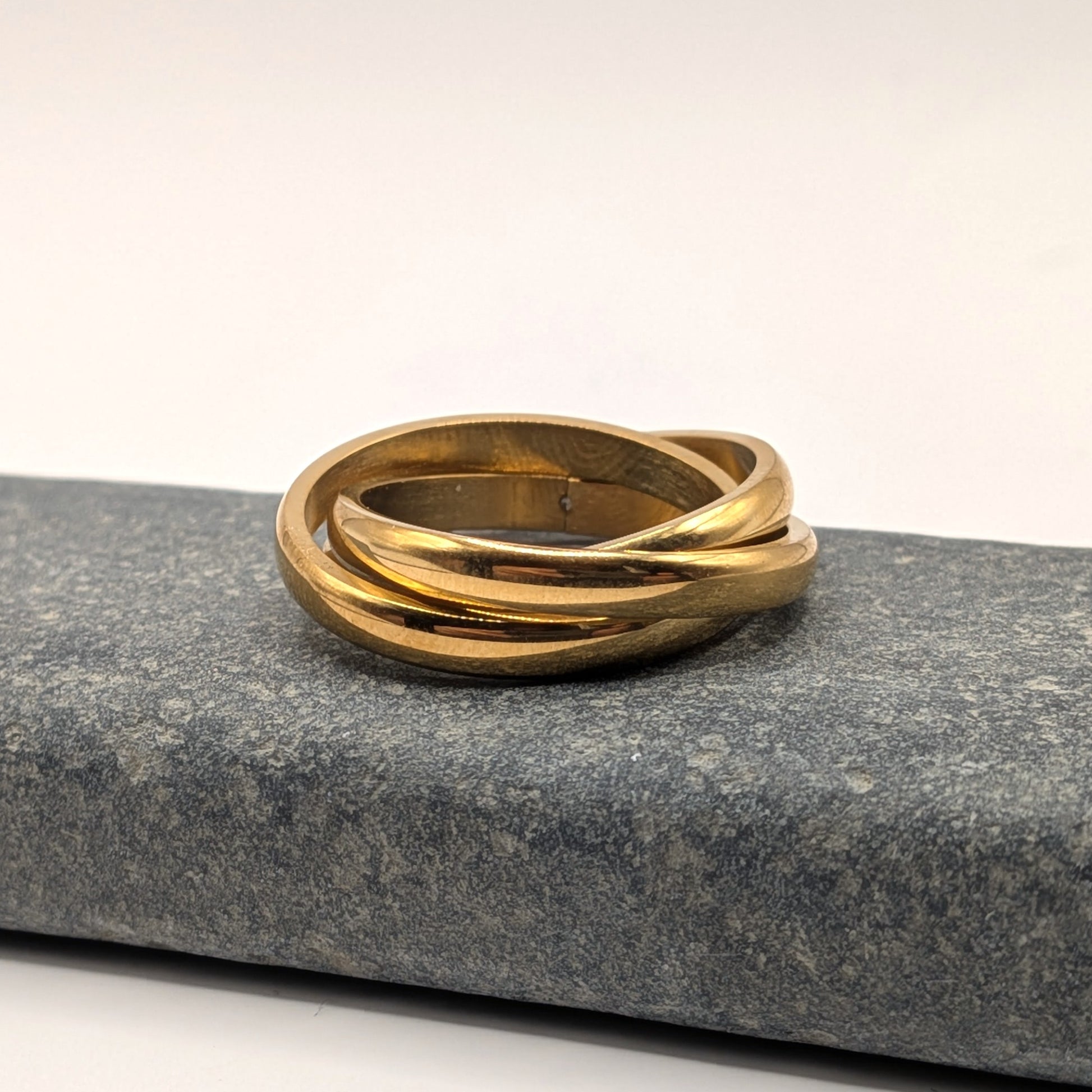 Gold ring with a wavy design on a gray stone surface