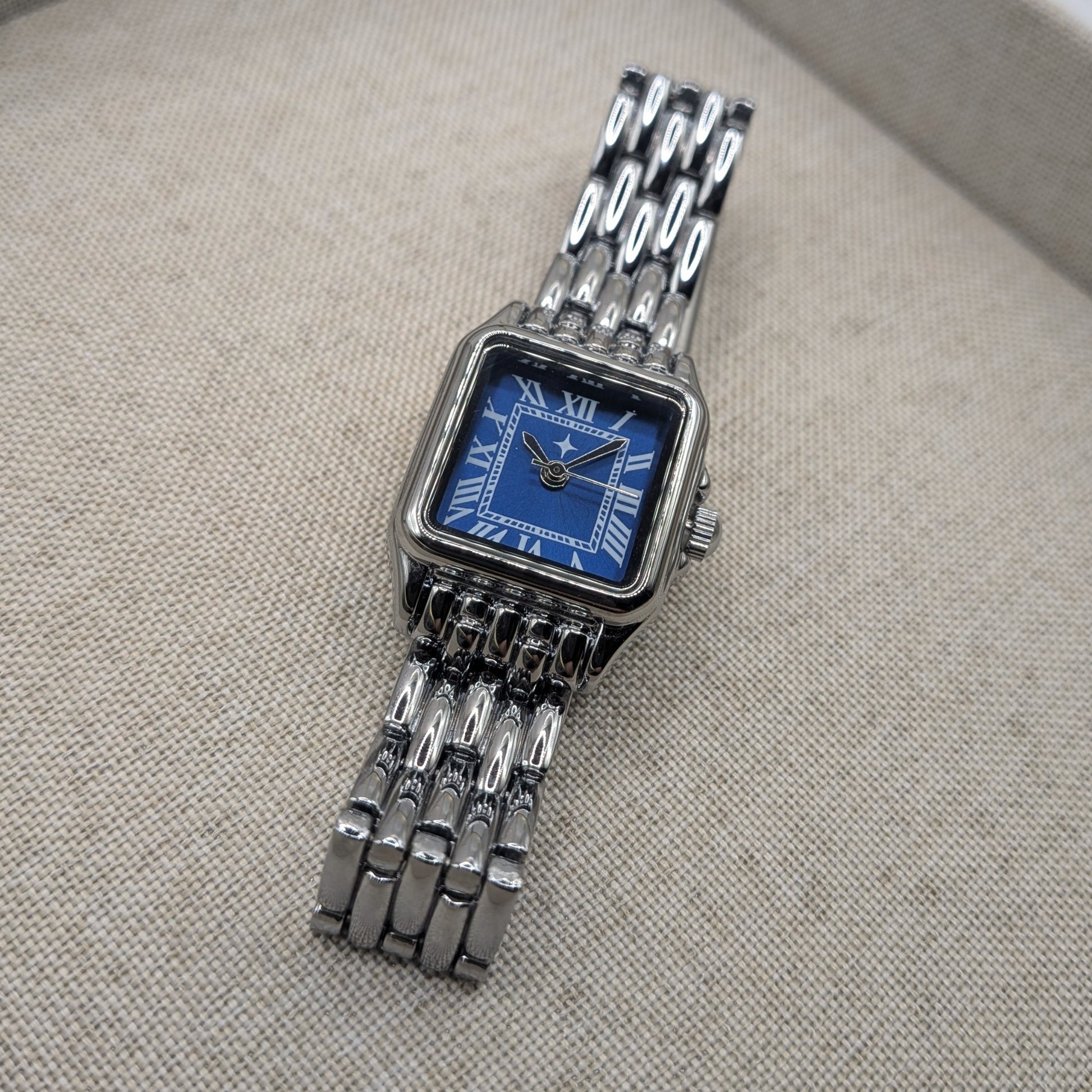 Silver watch with a blue face on a textured gray surface