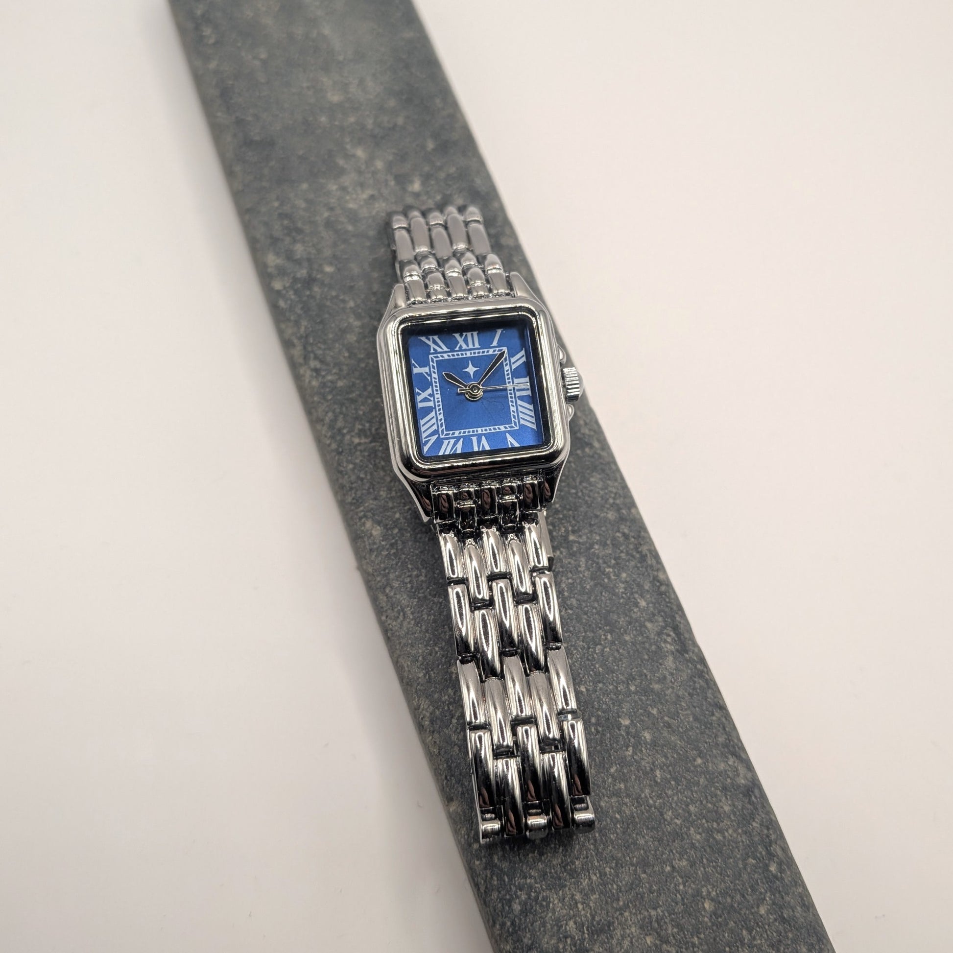 Silver watch with a blue face on a gray surface